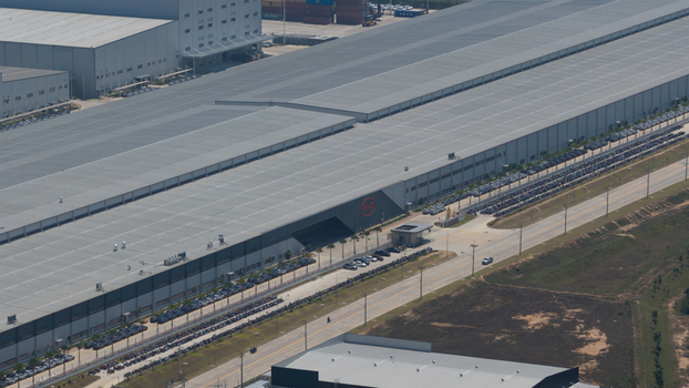 Aerial view of the BYD Auto Thailand factory showing the large industrial warehouse and rows of new electric vehicles in the parking lots in Phananikhom Rayong Thailand.