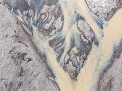 Aerial view of a braided river with sediment rich glacial water flowing through dark volcanic gravel beds in Iceland. Aerial view of a braided river with sediment rich glacial water flowing through dark volcanic gravel beds in Iceland.