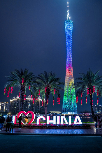 Guangzhou Guangdong Province China 24 February 2024 View of Canton Tower illuminated in rainbow colors at night with an I Love China sign palm trees and red lanterns. Guangzhou Guangdong Province China 24 February 2024 View of Canton Tower illuminated in rainbow colors at night with an I Love China sign palm trees and red lanterns.