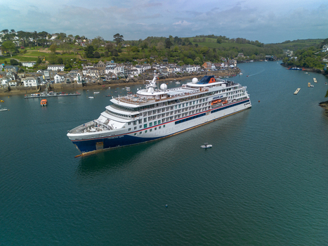 Fowey Cornwall United Kingdom 01 May 2026 Aerial view of a cruise ship in the Fowey River with the historic town green hills and small boats visible in the background. Fowey Cornwall United Kingdom 01 May 2026 Aerial view of a cruise ship in the Fowey River with the historic town green hills and small boats visible in the background.