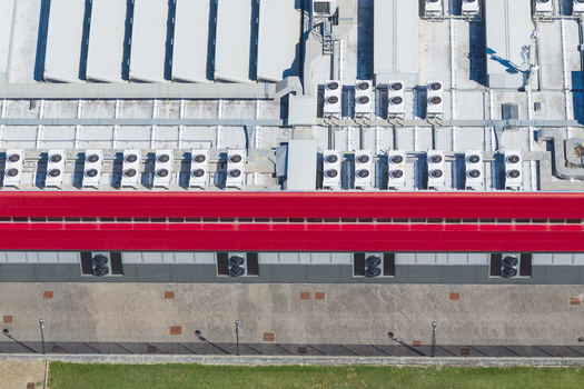 Aerial view of a modern data center facility featuring rows of industrial HVAC cooling units on the rooftop and a red facade in Arezzo Tuscany Italy. Aerial view of a modern data center facility featuring rows of industrial HVAC cooling units on the rooftop and a red facade in Arezzo Tuscany Italy.