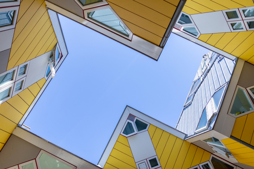 View of the iconic yellow Cube Houses with their unique geometric architecture against a clear blue sky in Rotterdam South Holland Netherlands. View of the iconic yellow Cube Houses with their unique geometric architecture against a clear blue sky in Rotterdam South Holland Netherlands.