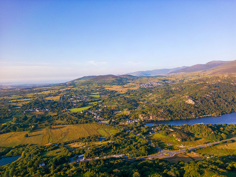 Aerial view of the village of Cwm y glo nestled among rolling green hills lush fields and the serene waters of Llyn Padarn in Cwm y glo Wales United Kingdom. Aerial view of the village of Cwm y glo nestled among rolling green hills lush fields and the serene waters of Llyn Padarn in Cwm y glo Wales United Kingdom.
