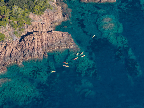 Aerial view of Le Trayas with kayakers paddling in the clear turquoise waters along the rugged red rocky coastline in Saint Raphael Provence Alpes Cote d Azur France. Aerial view of Le Trayas with kayakers paddling in the clear turquoise waters along the rugged red rocky coastline in Saint Raphael Provence Alpes Cote d Azur France.