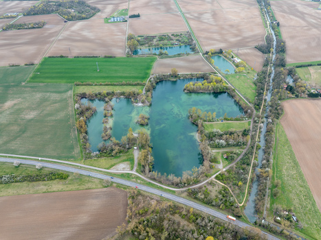 Aerial view of shimmering lakes nestled amidst a patchwork of agricultural fields creating a vibrant mosaic of earth tones Neuf Brisach Grand Est France.