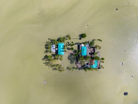Aerial view of houses with green roofs on a small island surrounded by floodwaters in Banshkhali Upazila Chittagong Division Bangladesh. Aerial view of houses with green roofs on a small island surrounded by floodwaters in Banshkhali Upazila Chittagong Division Bangladesh.
