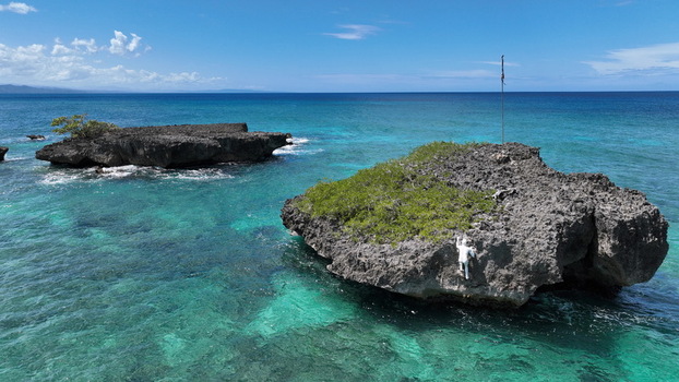 Aerial view of rocky islets near La Casita de Playa with turquoise waters and a statue on the cliffside in Rio San Juan Maria Trinidad Sanchez Dominican Republic.
