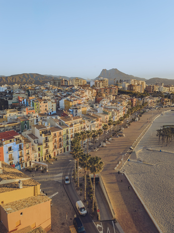 Aerial view of colorful houses along the waterfront a sandy beach with palm trees and mountains under a clear sky in La Vila Joiosa Valencian Community Spain. Aerial view of colorful houses along the waterfront a sandy beach with palm trees and mountains under a clear sky in La Vila Joiosa Valencian Community Spain.