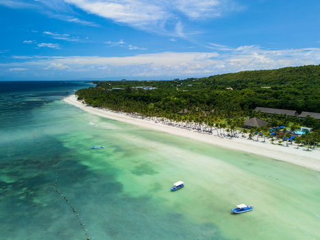 Aerial view of Dumaluan Beach with turquoise waters white sand palm trees and small boats anchored in the shallow sea in Panglao Central Visayas Philippines.