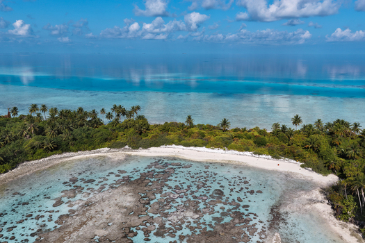 Aerial view of lush tropical islands with green palm trees and turquoise coral reefs surrounded by the deep blue ocean under a clear sky near Vaanee Dhaalu Atoll Maldives. Aerial view of lush tropical islands with green palm trees and turquoise coral reefs surrounded by the deep blue ocean under a clear sky near Vaanee Dhaalu Atoll Maldives.