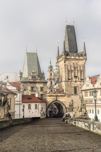 View of the Charles Bridge and Lesser Town Bridge Tower with historic statues and cobblestone path under an overcast sky Prague Prague Czechia. View of the Charles Bridge and Lesser Town Bridge Tower with historic statues and cobblestone path under an overcast sky Prague Prague Czechia.