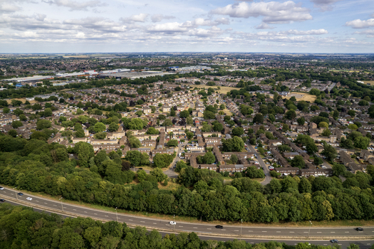 Aerial view of Bretton Park featuring residential housing lush green trees and a nearby highway under a blue sky with scattered clouds in Peterborough England United Kingdom. Aerial view of Bretton Park featuring residential housing lush green trees and a nearby highway under a blue sky with scattered clouds in Peterborough England United Kingdom.