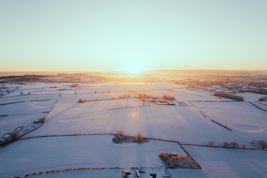 Aerial view of snow covered fields and hedgerows in the rural landscape at sunrise in Marston England United Kingdom. Aerial view of snow covered fields and hedgerows in the rural landscape at sunrise in Marston England United Kingdom.