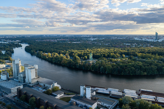 Aerial view of Spreepark surrounded by lush greenery and the Spree river with industrial buildings and barges in Berlin Berlin Germany. Aerial view of Spreepark surrounded by lush greenery and the Spree river with industrial buildings and barges in Berlin Berlin Germany.