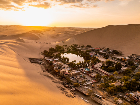 Aerial view of the Huacachina oasis surrounded by vast sand dunes at sunset in Huacachina Ica Peru. Aerial view of the Huacachina oasis surrounded by vast sand dunes at sunset in Huacachina Ica Peru.