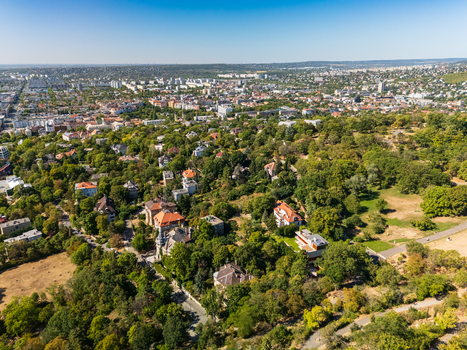 Aerial view of leafy residential neighborhoods parks and dense cityscape across Buda Budapest Hungary with the Buda Hills on the horizon in summer. Aerial view of leafy residential neighborhoods parks and dense cityscape across Buda Budapest Hungary with the Buda Hills on the horizon in summer.