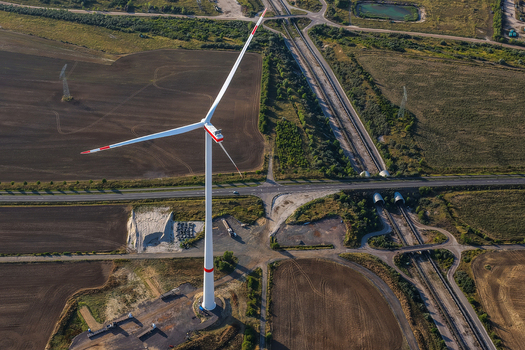 Aerial view of a wind turbine near the lignite open cast mine Schleenhain surrounded by agricultural fields roads and railway tracks in Zwenkau Saxony Germany.