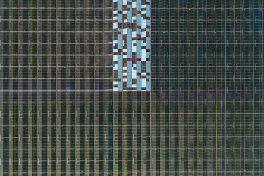 Aerial view of the geometric glass roofs of a large industrial greenhouse complex with reflective panels Hrusky South Moravian Region Czechia. Aerial view of the geometric glass roofs of a large industrial greenhouse complex with reflective panels Hrusky South Moravian Region Czechia.