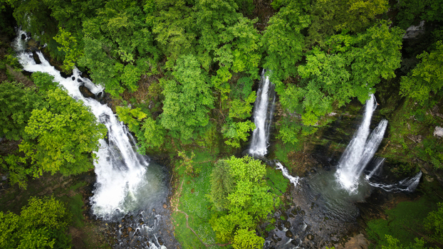 Aerial view of Cascades du Flumen with multiple waterfalls plunging into rocky pools surrounded by dense green forest in Septmoncel Les Molunes Bourgogne Franche Comte France. Aerial view of Cascades du Flumen with multiple waterfalls plunging into rocky pools surrounded by dense green forest in Septmoncel Les Molunes Bourgogne Franche Comte France.
