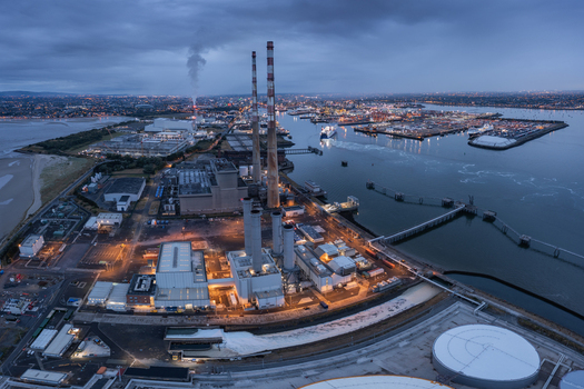 Aerial view of Poolbeg Power Station with its tall red and white chimneys overlooking Dublin Port and the bay at twilight in Dublin 4 County Dublin Ireland. Aerial view of Poolbeg Power Station with its tall red and white chimneys overlooking Dublin Port and the bay at twilight in Dublin 4 County Dublin Ireland.