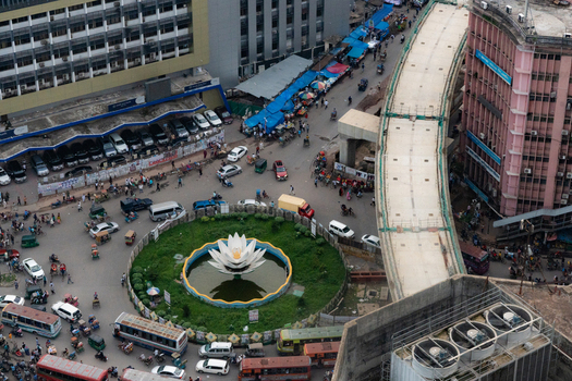 Dhaka Bangladesh 30 June 2025 Aerial view of the Shapla Chattar roundabout featuring its iconic water lily sculpture surrounded by busy city streets traffic and urban infrastructure.