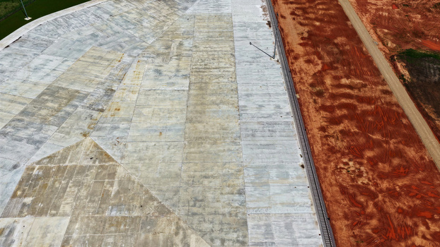 Aerial view of a large concrete construction site adjacent to a red earth field in Latvia. Aerial view of a large concrete construction site adjacent to a red earth field in Latvia.