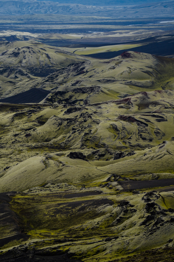 View of a rugged landscape unfolds with moss covered lava fields stretching towards distant mountains under a vast sky Skaftárhreppur Iceland. View of a rugged landscape unfolds with moss covered lava fields stretching towards distant mountains under a vast sky Skaftárhreppur Iceland.