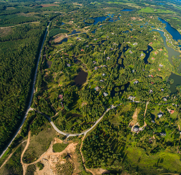 Aerial view of a lush green landscape featuring numerous small lakes dense forests and scattered residential houses connected by winding roads in Latvia. Aerial view of a lush green landscape featuring numerous small lakes dense forests and scattered residential houses connected by winding roads in Latvia.