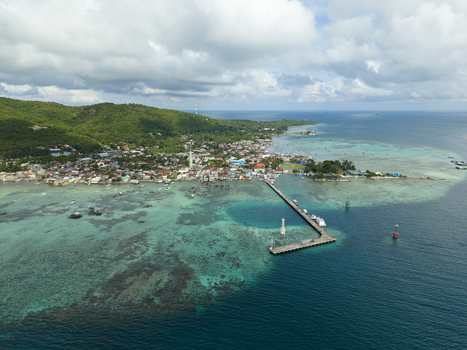 Aerial view of a pier stretching out into the turquoise sea from a vibrant coastal town nestled beneath verdant hills Karimunjawa Central Java Indonesia. Aerial view of a pier stretching out into the turquoise sea from a vibrant coastal town nestled beneath verdant hills Karimunjawa Central Java Indonesia.