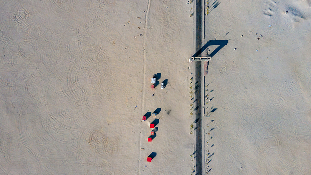 Aerial view of Sarfaranga Cold Desert Shigar with tire tracks on the sand a straight road and small structures casting long shadows in Skardu Gilgit Pakistan.