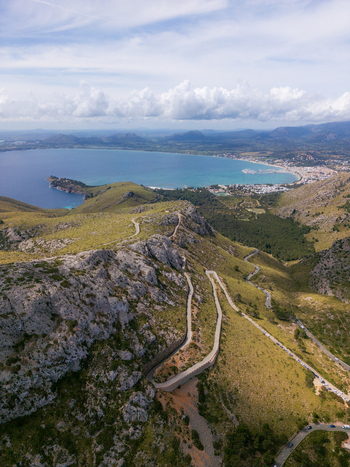 Aerial view of the winding mountain road leading to Cap de Formentor with the turquoise bay and rugged cliffs in Balearic Islands Spain.