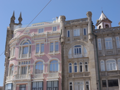 View of ornate historic buildings with a distinctive pink facade and intricate stone architectural details under a clear blue sky in Porto Porto District Portugal. View of ornate historic buildings with a distinctive pink facade and intricate stone architectural details under a clear blue sky in Porto Porto District Portugal.
