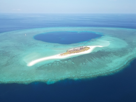 Aerial view of Pulau Ndaa a small tropical island with white sand beaches surrounded by a vibrant turquoise coral reef and deep blue sea in Tomia South East Sulawesi Indonesia.