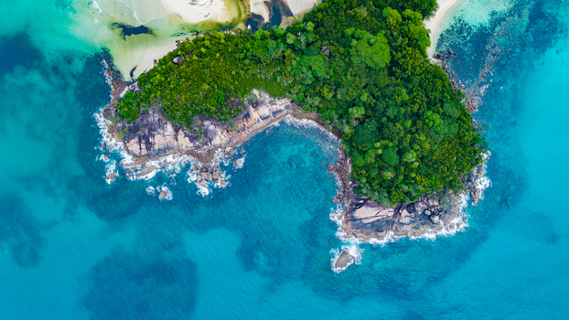 Aerial view of the lush tropical coastline with dense green vegetation rocky outcrops and vibrant turquoise waters in Grand Anse Mahe Seychelles. Aerial view of the lush tropical coastline with dense green vegetation rocky outcrops and vibrant turquoise waters in Grand Anse Mahe Seychelles.