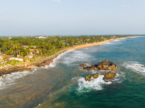 Aerial view of the tropical coastline with sandy beaches palm trees and rocky outcrops in Galle Southern Province Sri Lanka.