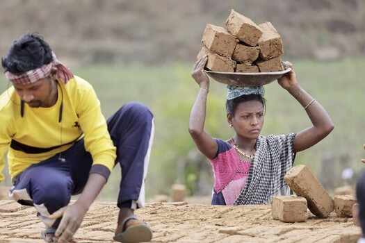 Odisha India 26 March 2026 View of workers amidst earthy tones one balancing bricks on her head the other focused on arranging them in the field. Odisha India 26 March 2026 View of workers amidst earthy tones one balancing bricks on her head the other focused on arranging them in the field.