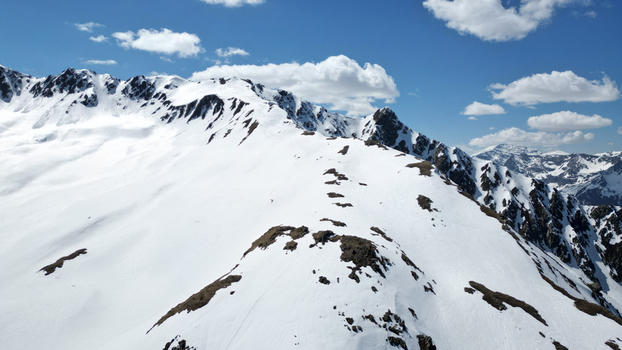 Aerial view of the snow covered Pointe Ronde mountain ridge with rocky outcrops under a blue sky with white clouds Trient Valais Switzerland.