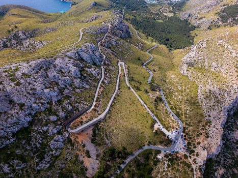 Aerial view of the winding mountain roads of Cap de Formentor surrounded by rocky cliffs and lush green vegetation in Balearic Islands Spain.
