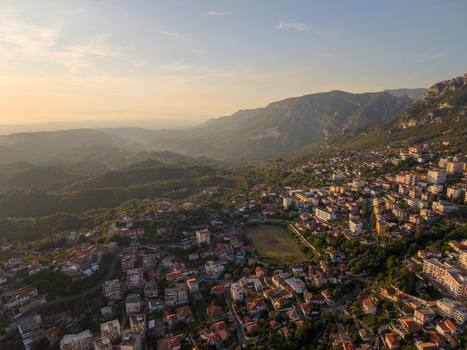 Aerial view of the historic town of Kruje with its traditional red roofed houses nestled against rugged mountain slopes during golden hour in Kruje Durres County Albania.