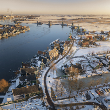 Aerial view of Zaanse Schans featuring traditional Dutch windmills snow covered historic wooden houses and frozen canals in Zaandam Noord Holland Netherlands. Aerial view of Zaanse Schans featuring traditional Dutch windmills snow covered historic wooden houses and frozen canals in Zaandam Noord Holland Netherlands.
