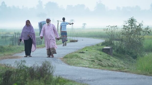 View of people walking on a rural road in Bogura Bangladesh.