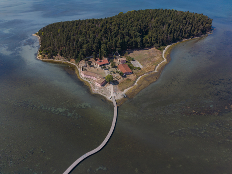 Aerial view of Zvernec Island featuring the historic Zvernec Monastery surrounded by forest and lagoon waters connected by a long wooden footbridge Vlore Vlore County Albania. Aerial view of Zvernec Island featuring the historic Zvernec Monastery surrounded by forest and lagoon waters connected by a long wooden footbridge Vlore Vlore County Albania.