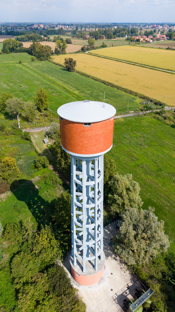 Aerial view of Torre dell Acquedotto Gruppo CAP surrounded by green agricultural fields and rural landscape in Mediglia Lombardy Italy.