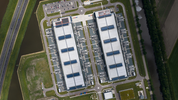 Aerial view of the Agriport data center complex featuring two large industrial buildings with rooftop cooling units and surrounding green fields in Middenmeer Noord Holland Netherlands. Aerial view of the Agriport data center complex featuring two large industrial buildings with rooftop cooling units and surrounding green fields in Middenmeer Noord Holland Netherlands.