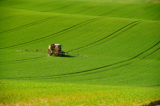 View of a tractor spraying a large rolling green field in the Moravia region in Brno City District South Moravian Region Czechia.