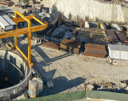 Aerial view of a busy construction site featuring a large yellow gantry crane a deep circular excavation shaft and stacks of rebar in Avcilar Istanbul Turkiye. Aerial view of a busy construction site featuring a large yellow gantry crane a deep circular excavation shaft and stacks of rebar in Avcilar Istanbul Turkiye.