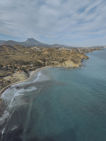 Aerial view of Torre del Xarco on a rocky cliff overlooking the turquoise Mediterranean Sea and Playa del Xarco beach in La Vila Joiosa Comunidad Valenciana Spain.