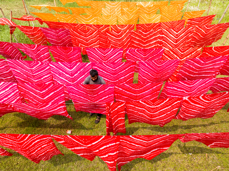 Narayanganj Bangladesh 30 March 2026 Aerial view of a man amid a vibrant display of colorful fabrics drying under the open sky creating a mesmerizing pattern of hues and textures.