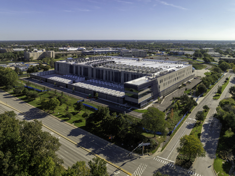 Aerial view of a large modern data center facility surrounded by green lawns and parking areas in Elk Grove Village Illinois United States.