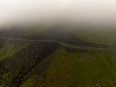 Aerial view of a winding road cutting through the lush green hills of the Eastern Region in Iceland. Aerial view of a winding road cutting through the lush green hills of the Eastern Region in Iceland.